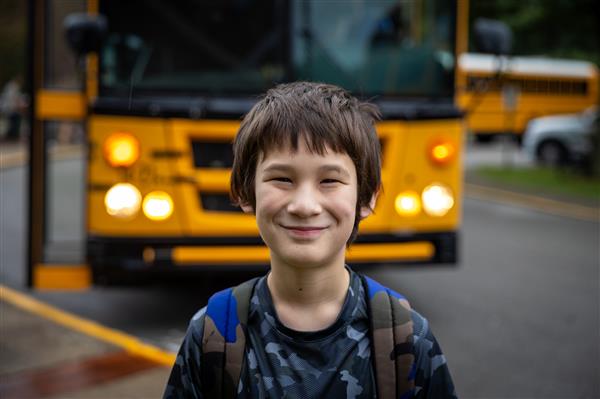 boy smiling with a bus behind him